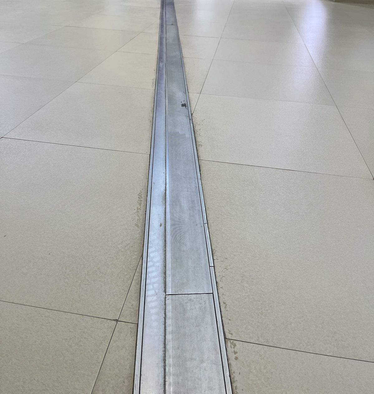 Aluminium floor expansion joint running across a tiled floor, Bengaluru