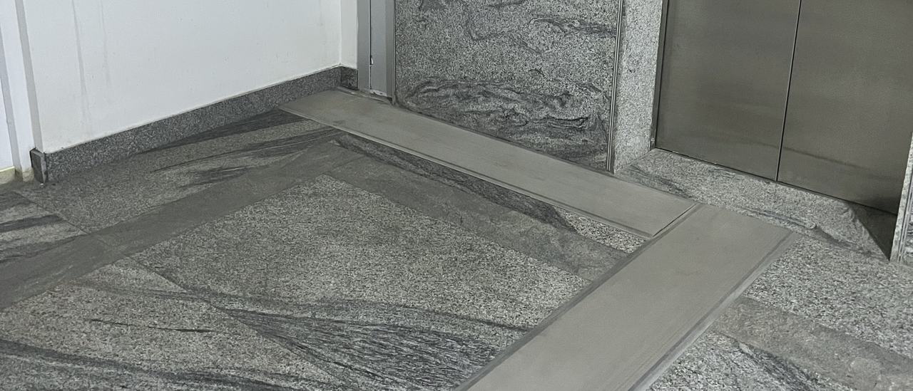 A floor expansion joint in a granite lift lobby turning up the wall, Bengaluru
