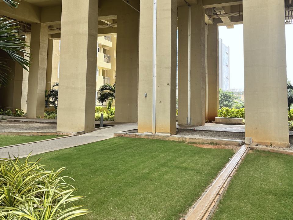 An expansion joint crossing a podium lawn and running up a column at Nikoo Homes 4, Bengaluru